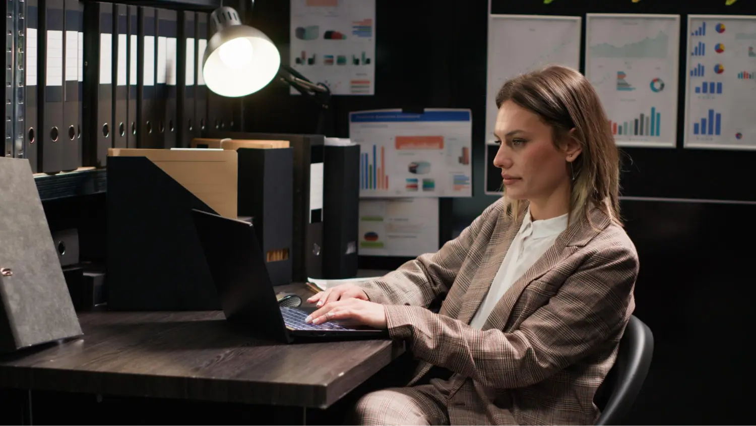 A specialist working on a laptop in an office with analytics reports
