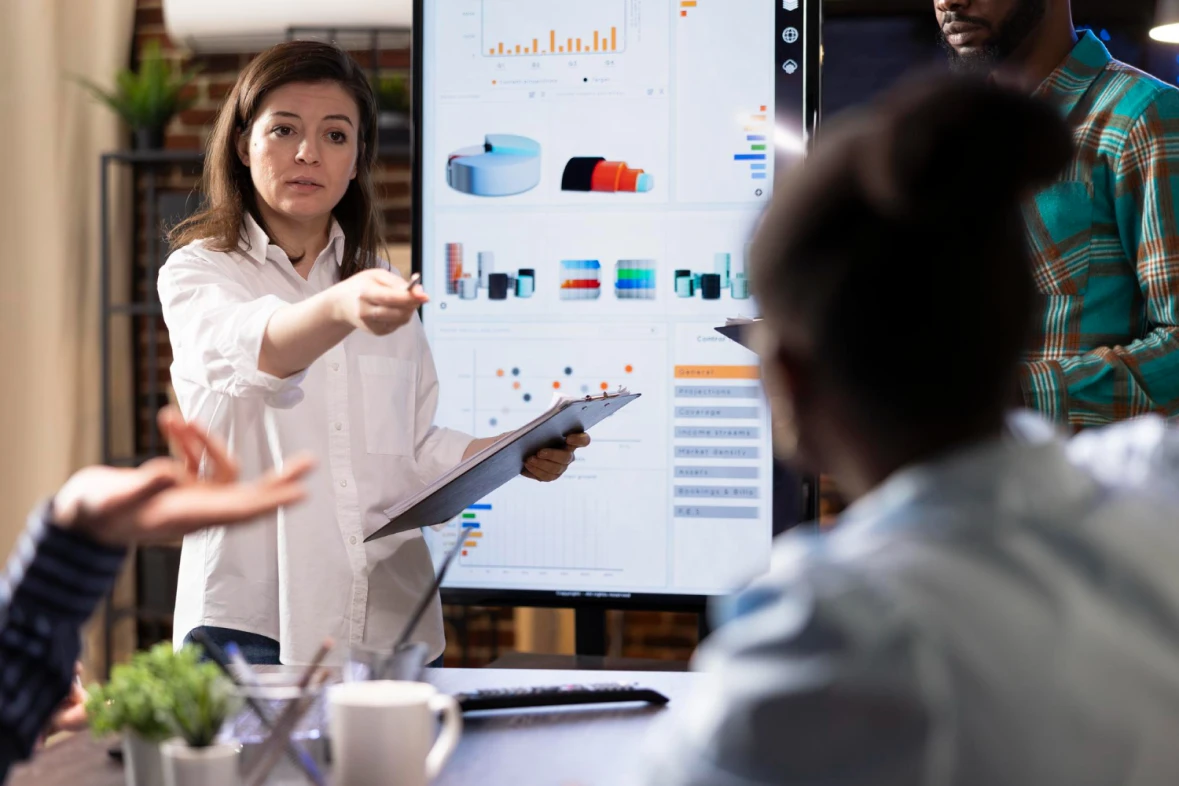 A team discusses the results of customer data analysis beside a screen with charts