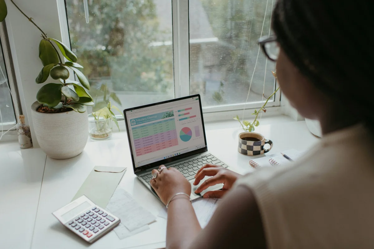 An analyst works with financial charts on a laptop, with a calculator nearby