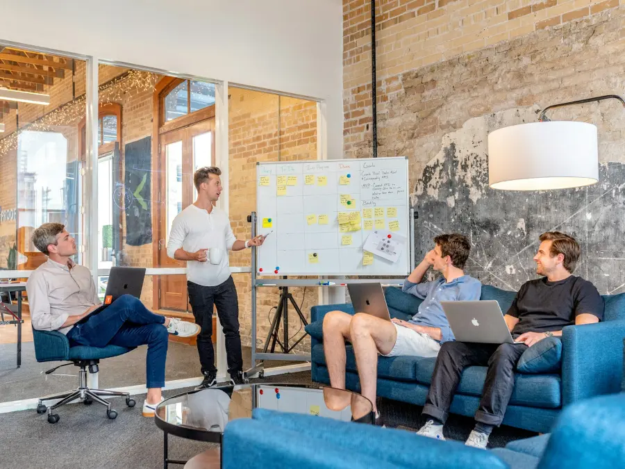 A team discusses loyalty program performance indicators beside a planning board