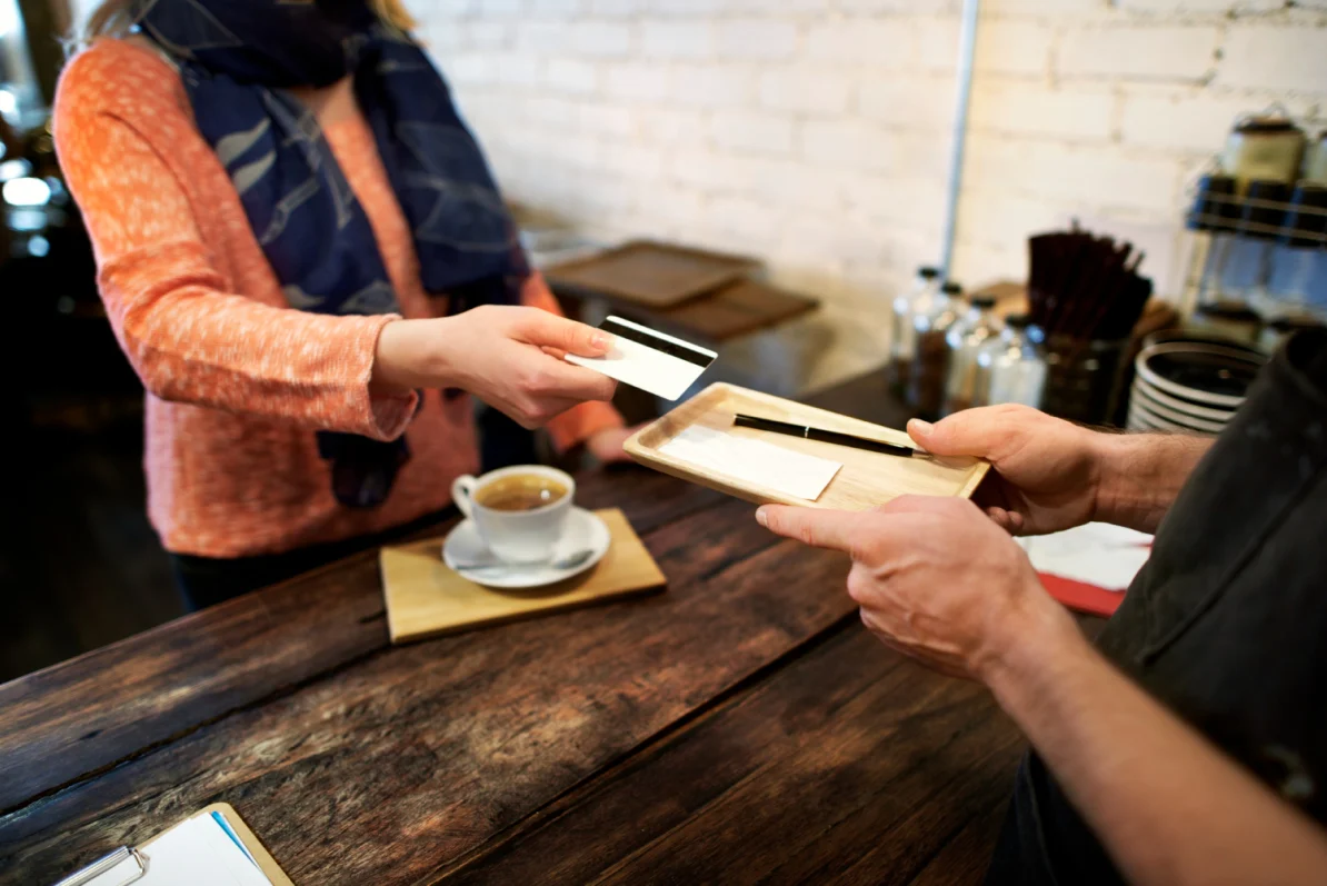 A customer pays for a repeat purchase by bank card in a coffee shop